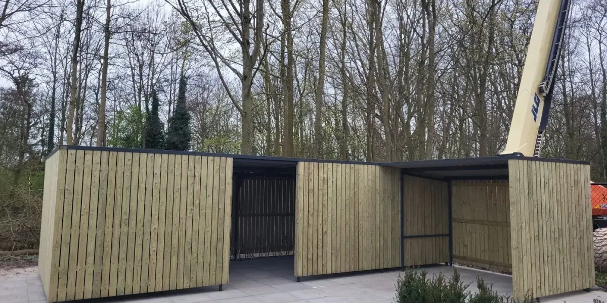 Overkapping naast fietsenstalling met inpandige dakgoot en damwandplaten