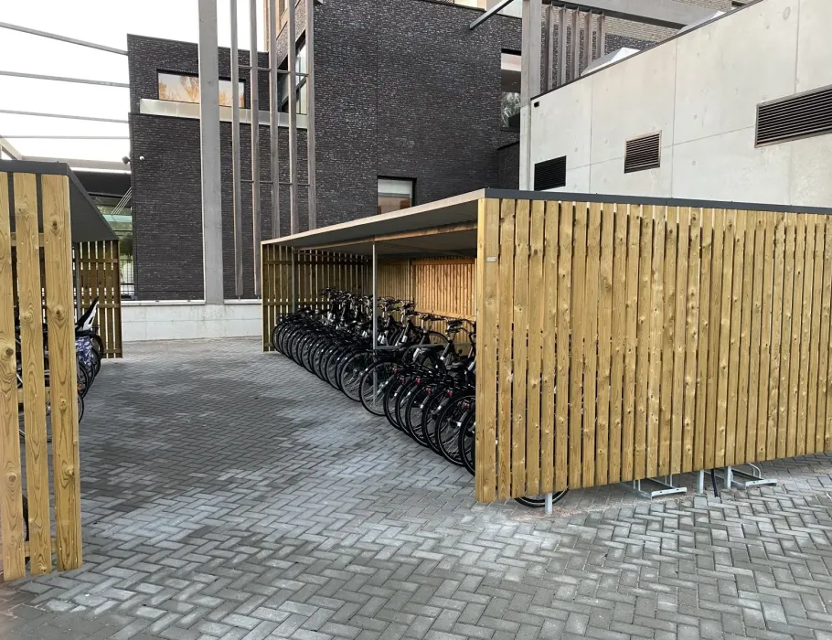 Overdekte fietsenstalling van hout en staal op bedrijfsterrein